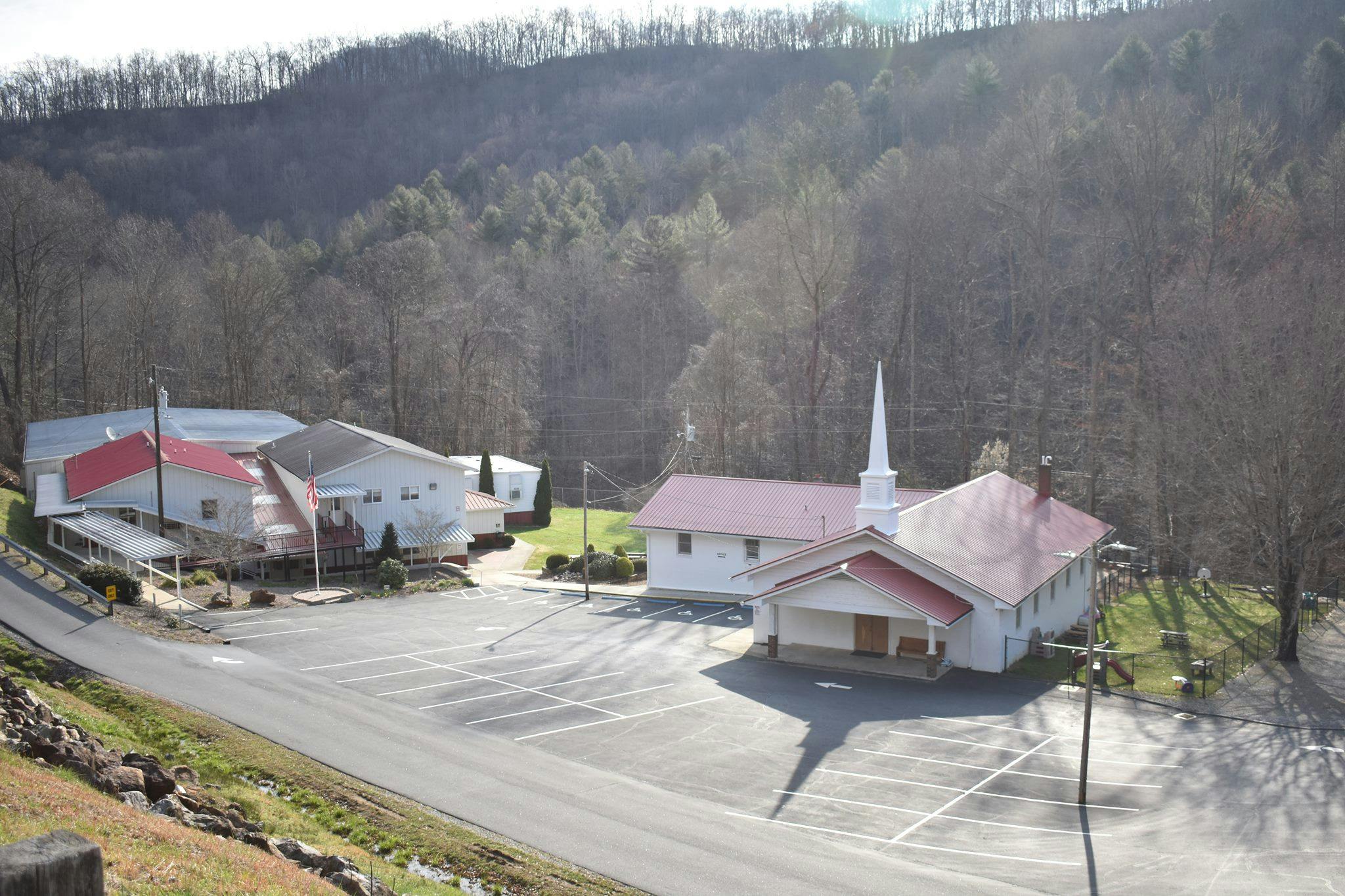 Church building with a steeple and an adjacent building with red roofs