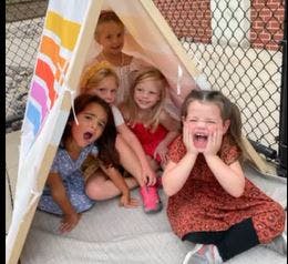 Five children playing in and around a small tent
