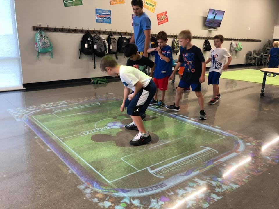 Children playing on an interactive floor projection of a soccer field