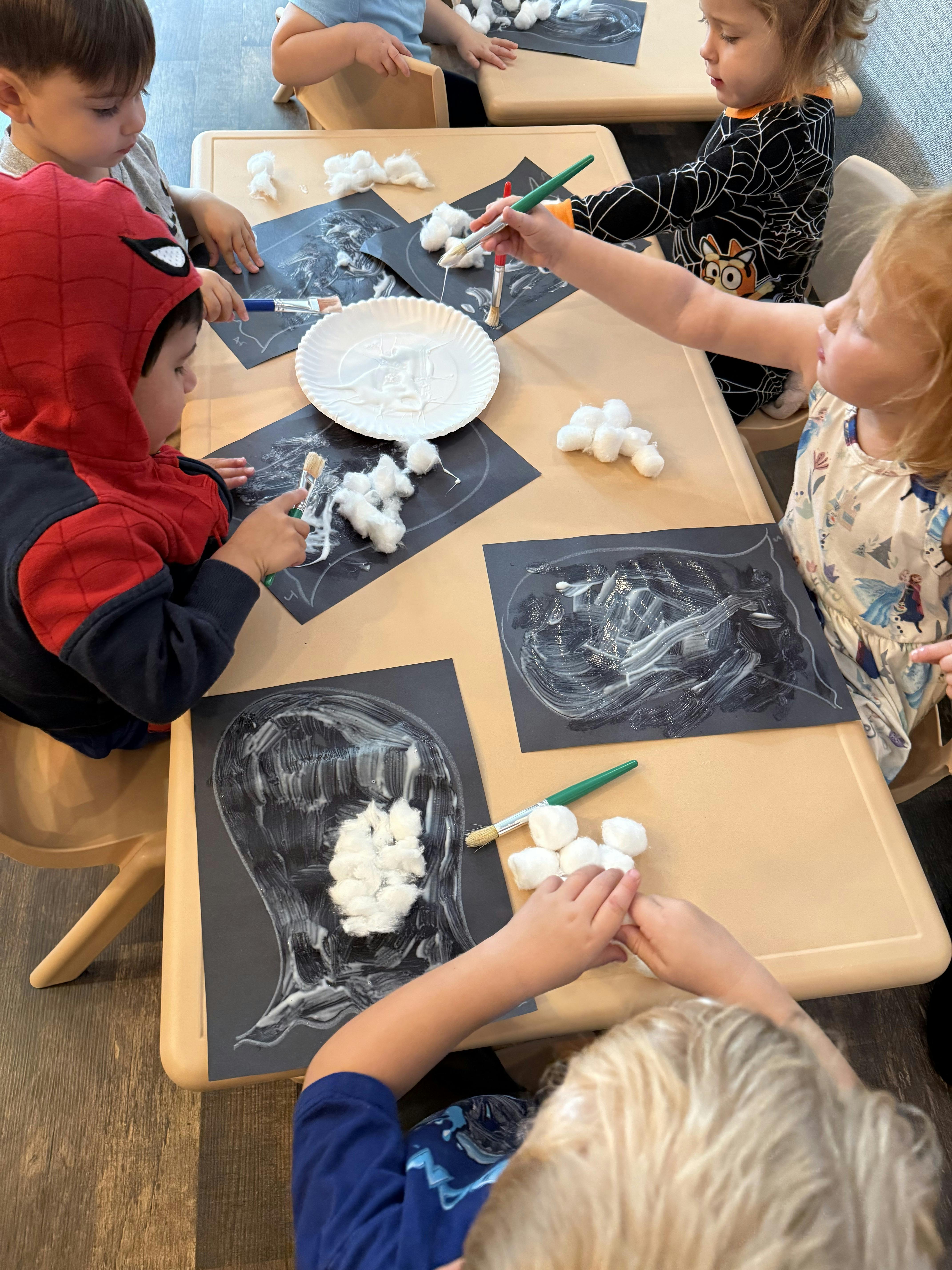 Children at a table doing an art project with cotton balls and glue