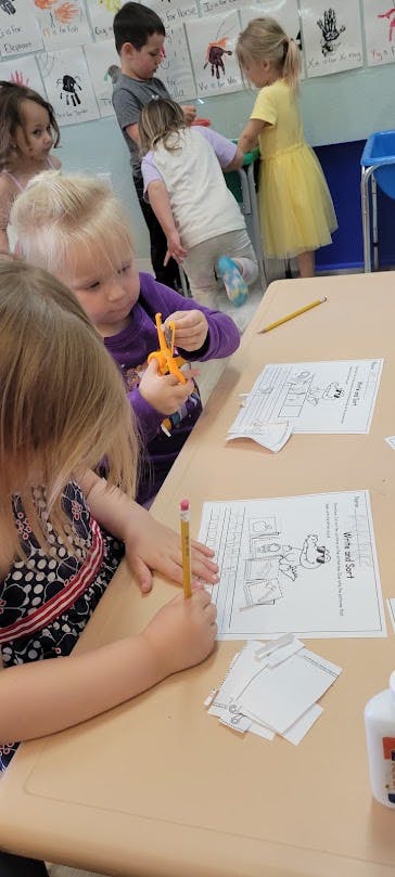 Children in a classroom, one child drawing at a desk
