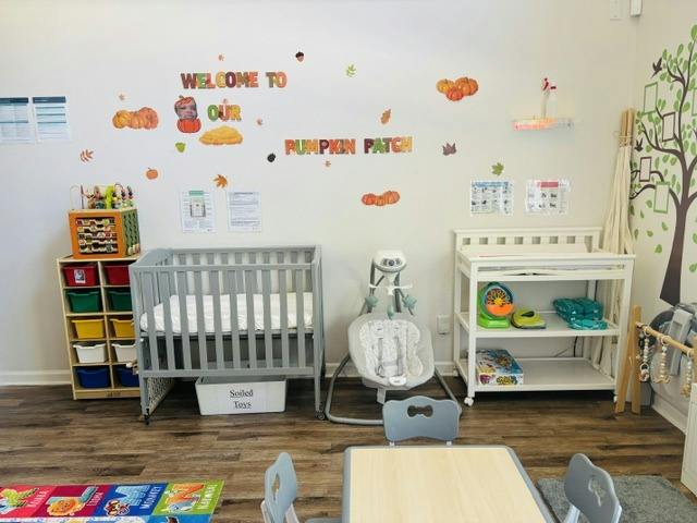 Crib and baby equipment in a childcare room with pumpkin patch wall decorations