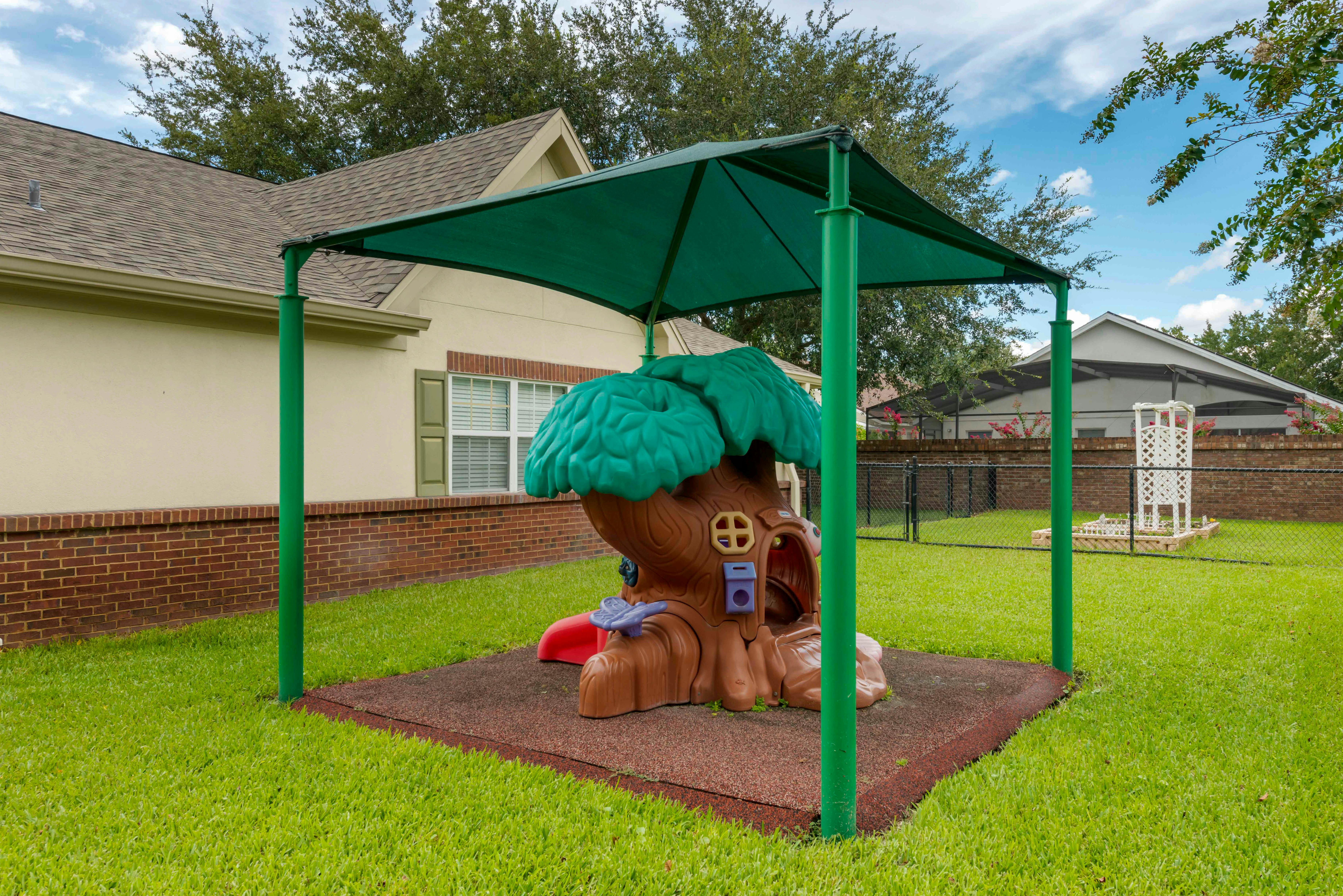 treehouse play structure under a green shade canopy on a playground