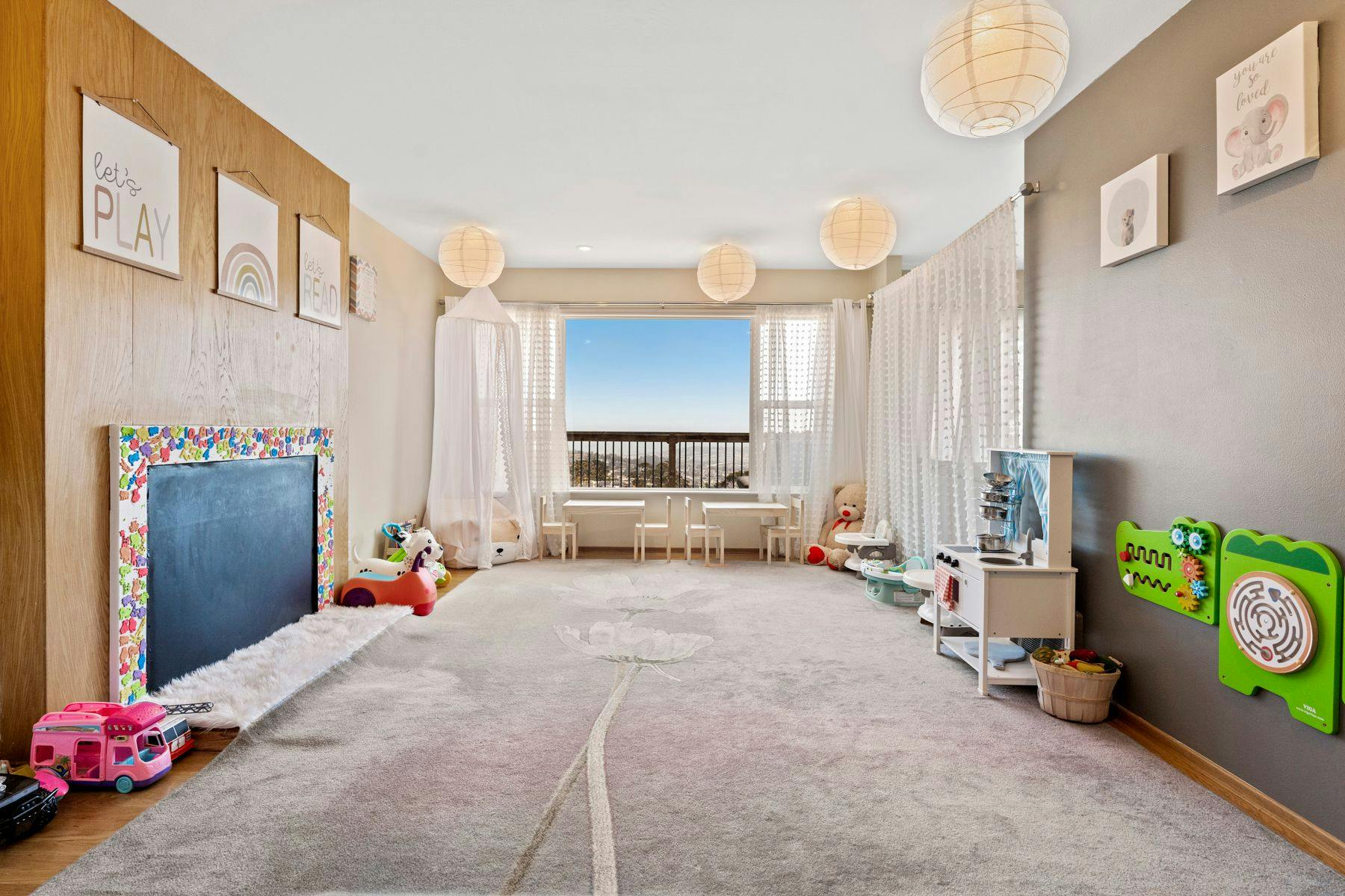 Playroom with a large rug, toys, and a window overlooking a city