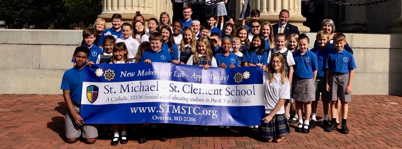 Group of children and adults holding a banner for St. Michael St. Clement School