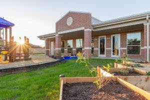 Building exterior with playground and garden beds