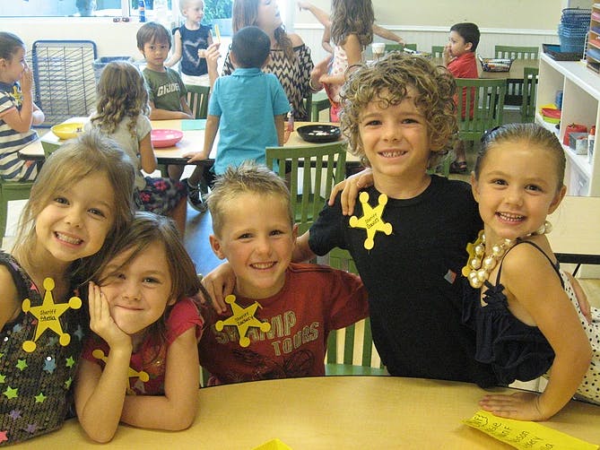 Five children wearing sheriff badges in a classroom