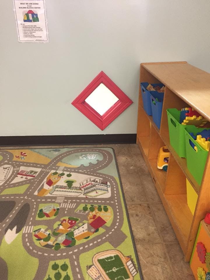 Playroom with a road map rug, toy shelf, and a red diamond-shaped window