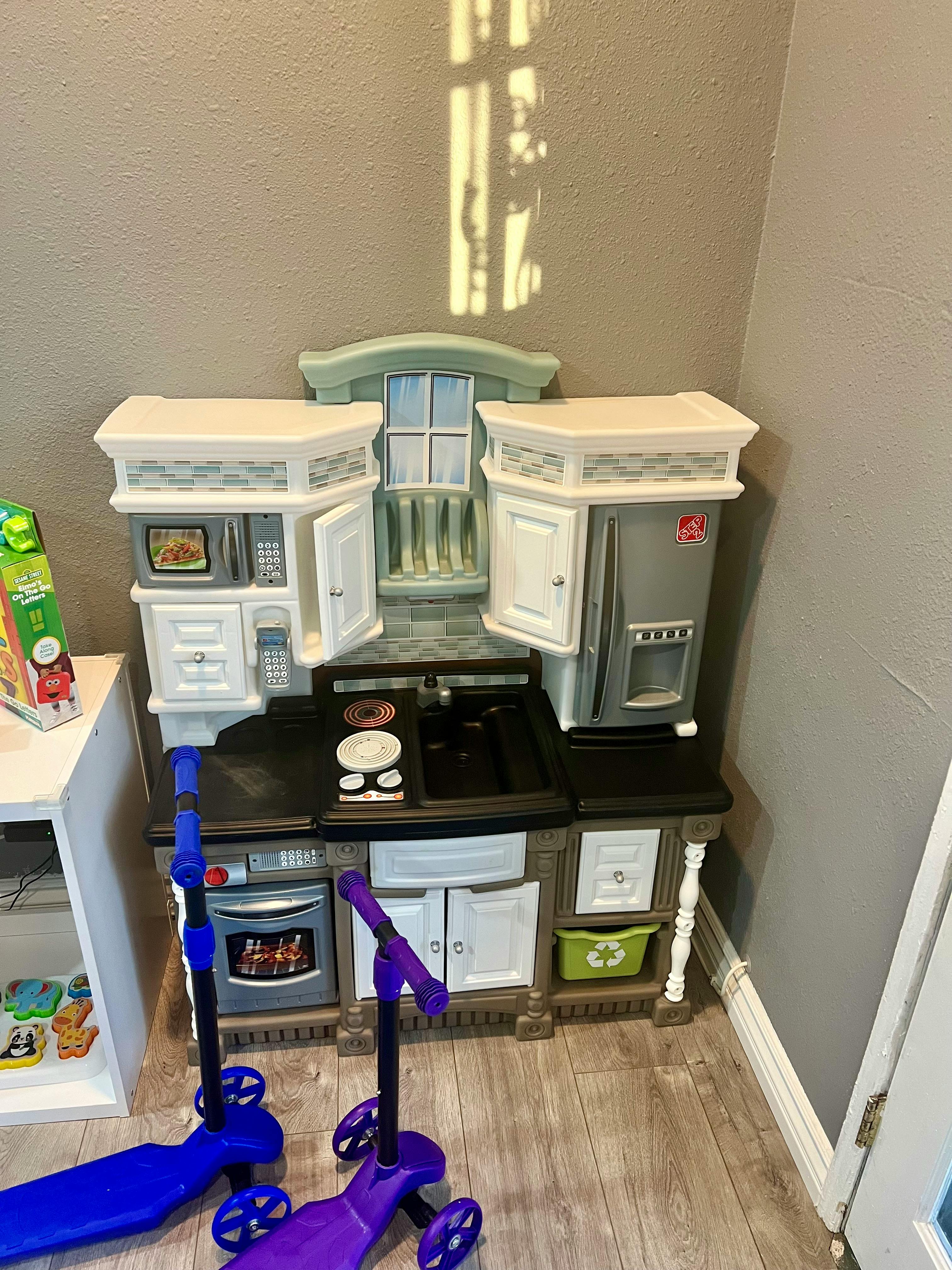 Toy kitchen set with two scooters in front