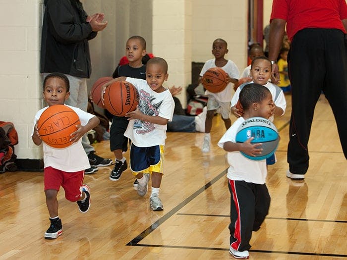 Children running with basketballs on a court