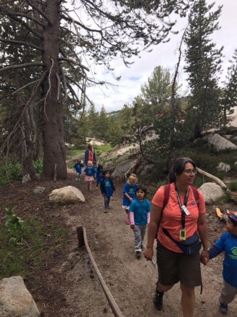 Adult and children walking on a dirt path in a wooded area