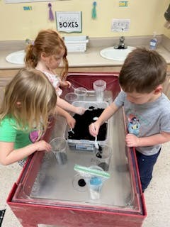 Three children playing at a water table