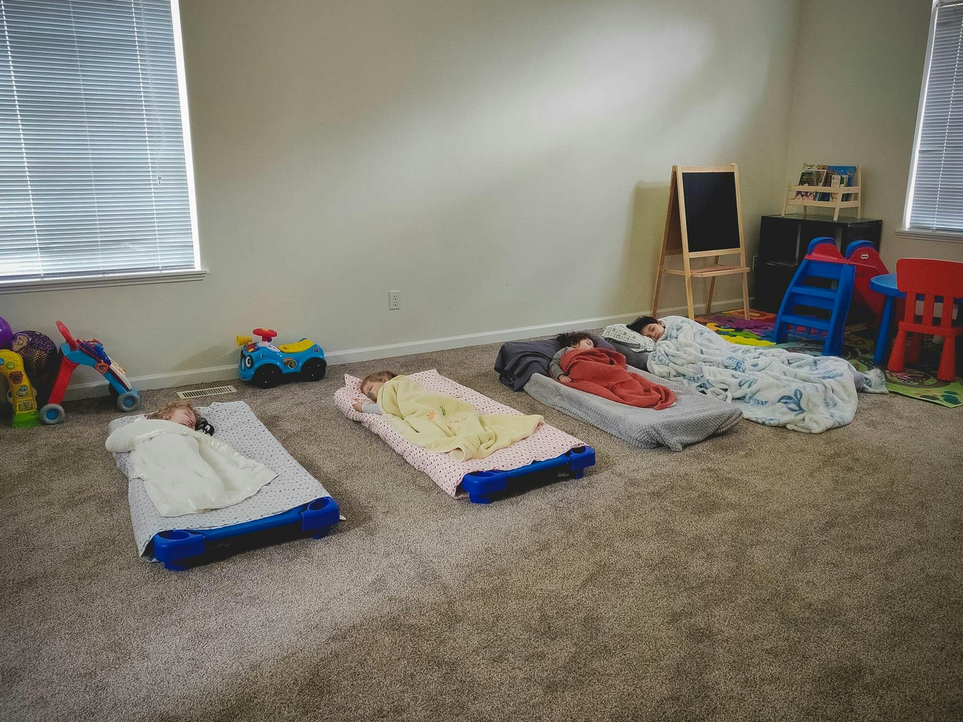 Four children sleeping on cots in a room