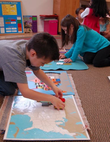 Child placing blocks on a map puzzle on the floor