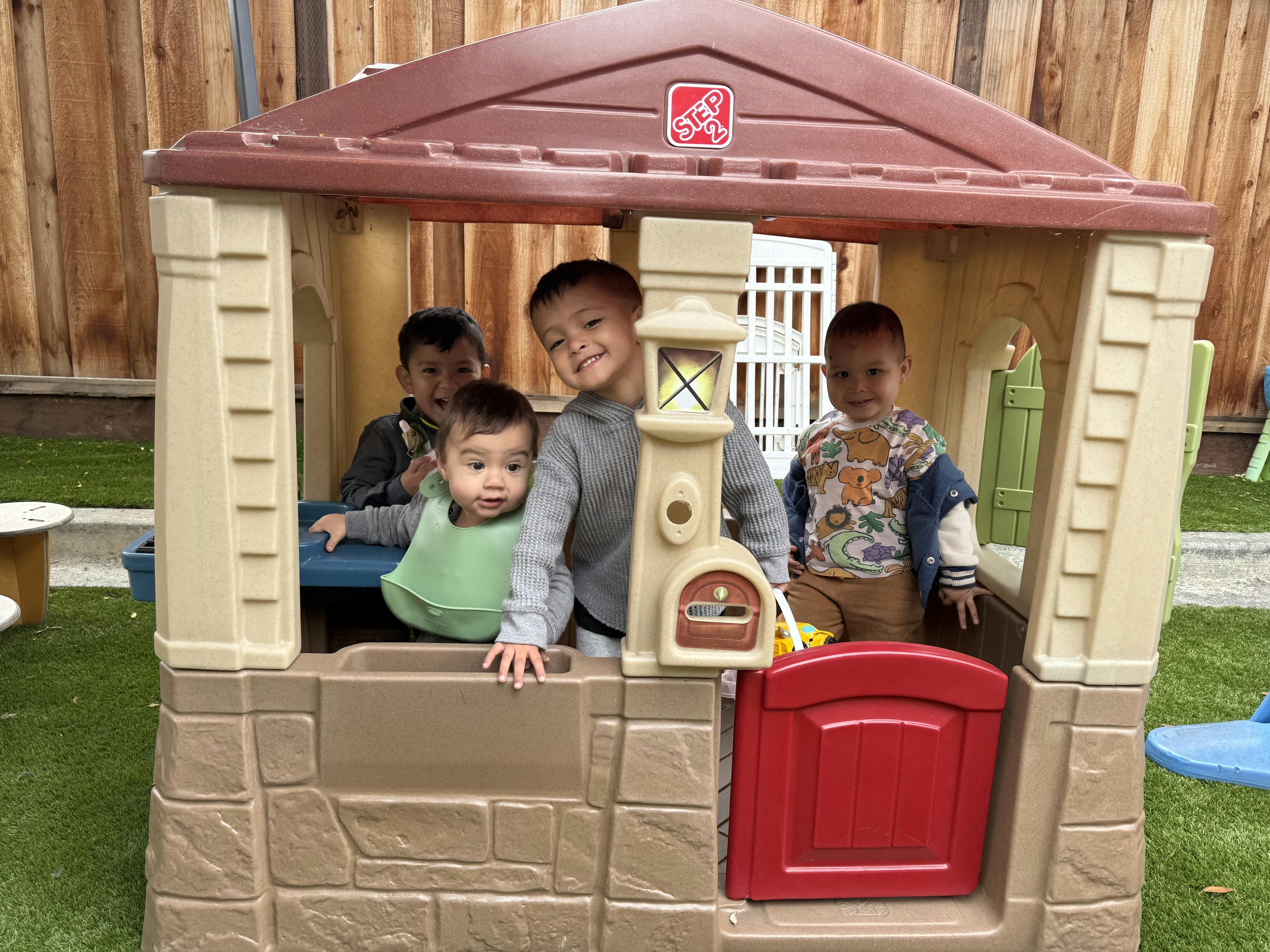 Four children playing in a toy house