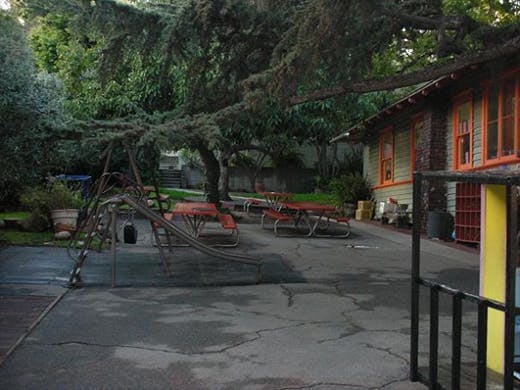 Playground with slide and picnic tables next to a building