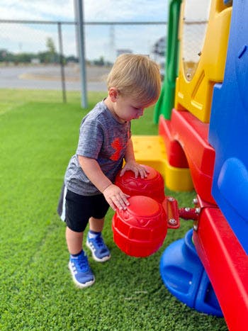 Child playing with red drums on a playground