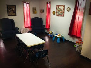 Room with two armchairs, a table, and children's toys