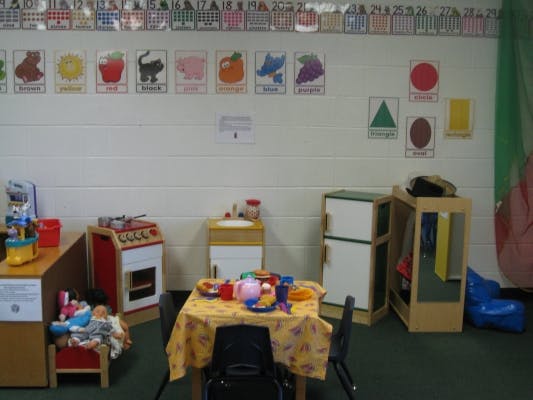 Play kitchen and table with toy dishes in a classroom