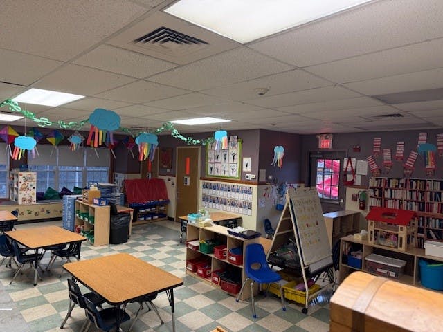 Empty classroom with tables, chairs, bookshelves, and decorations