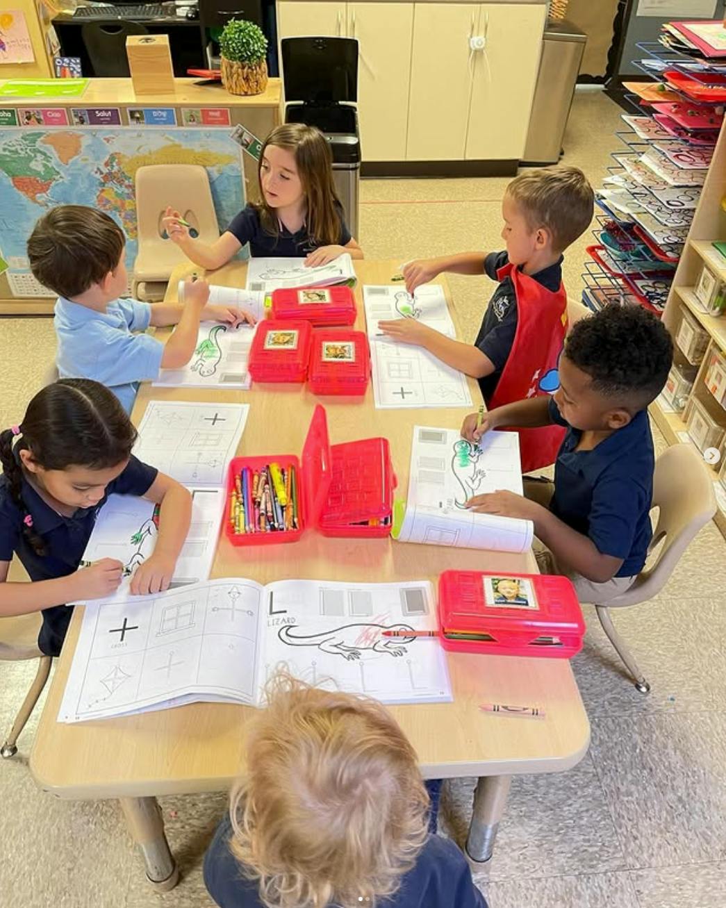 Several children sitting at a table coloring in a classroom