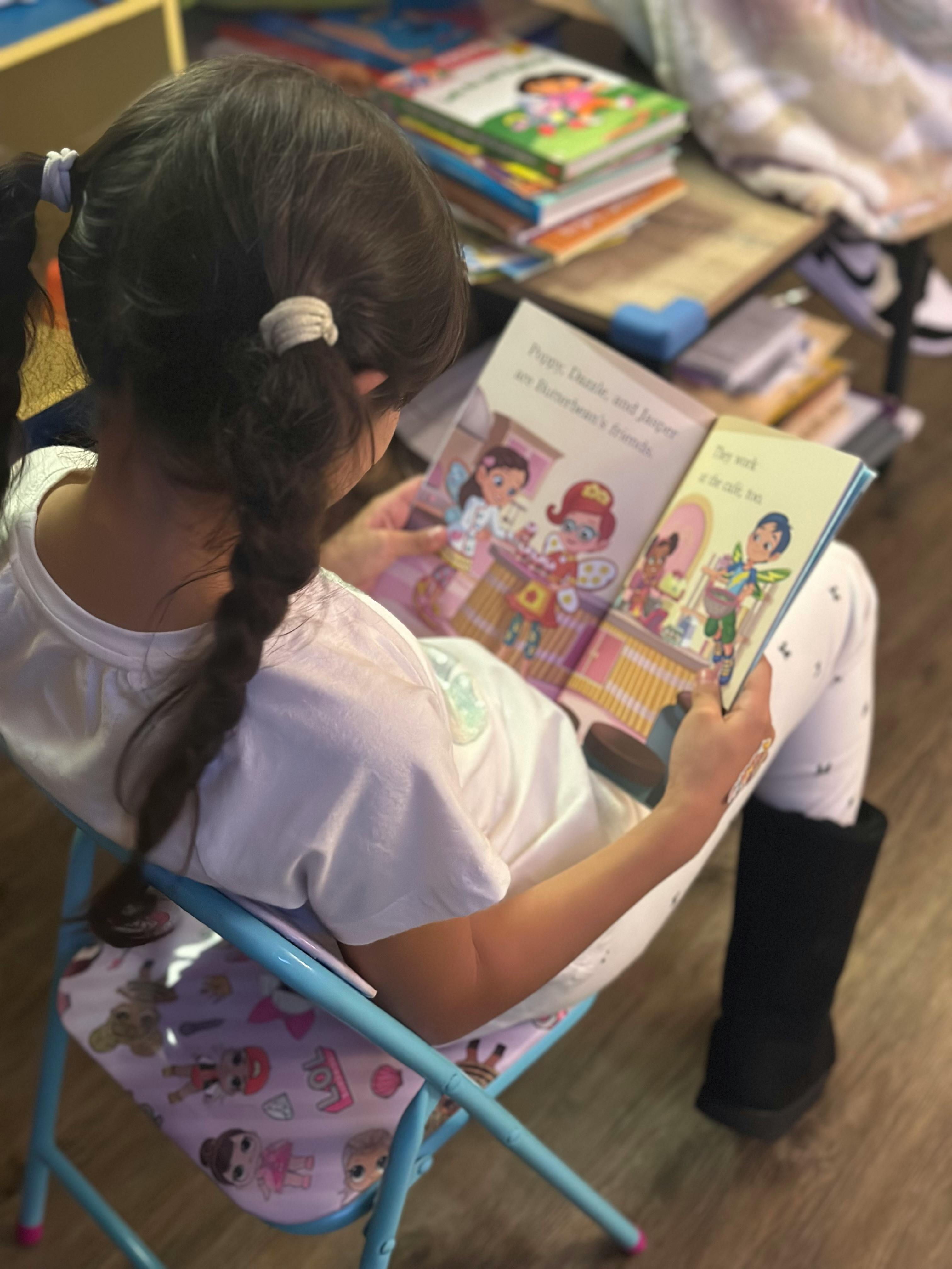 Child with braided pigtails sitting on a chair reading a book