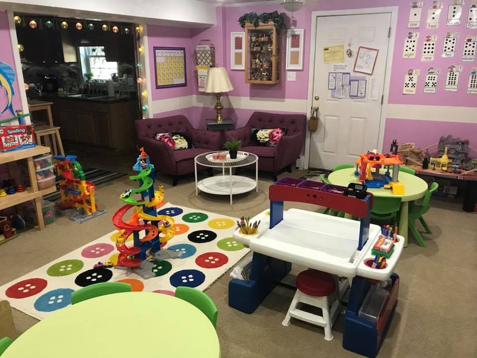 Playroom with a colorful rug, toys, small tables, and purple armchairs