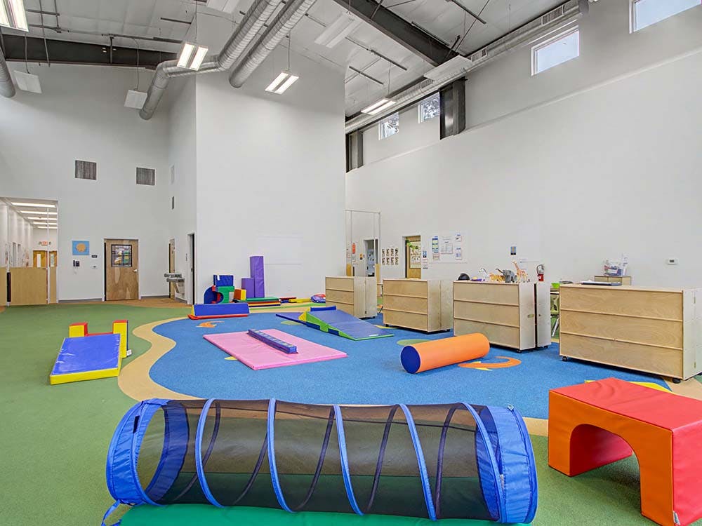 Playroom with colorful mats, a tunnel, and cubbies