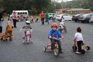 Children riding tricycles and bicycles in a parking lot