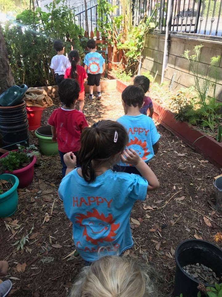 Children walking on a dirt path in a garden