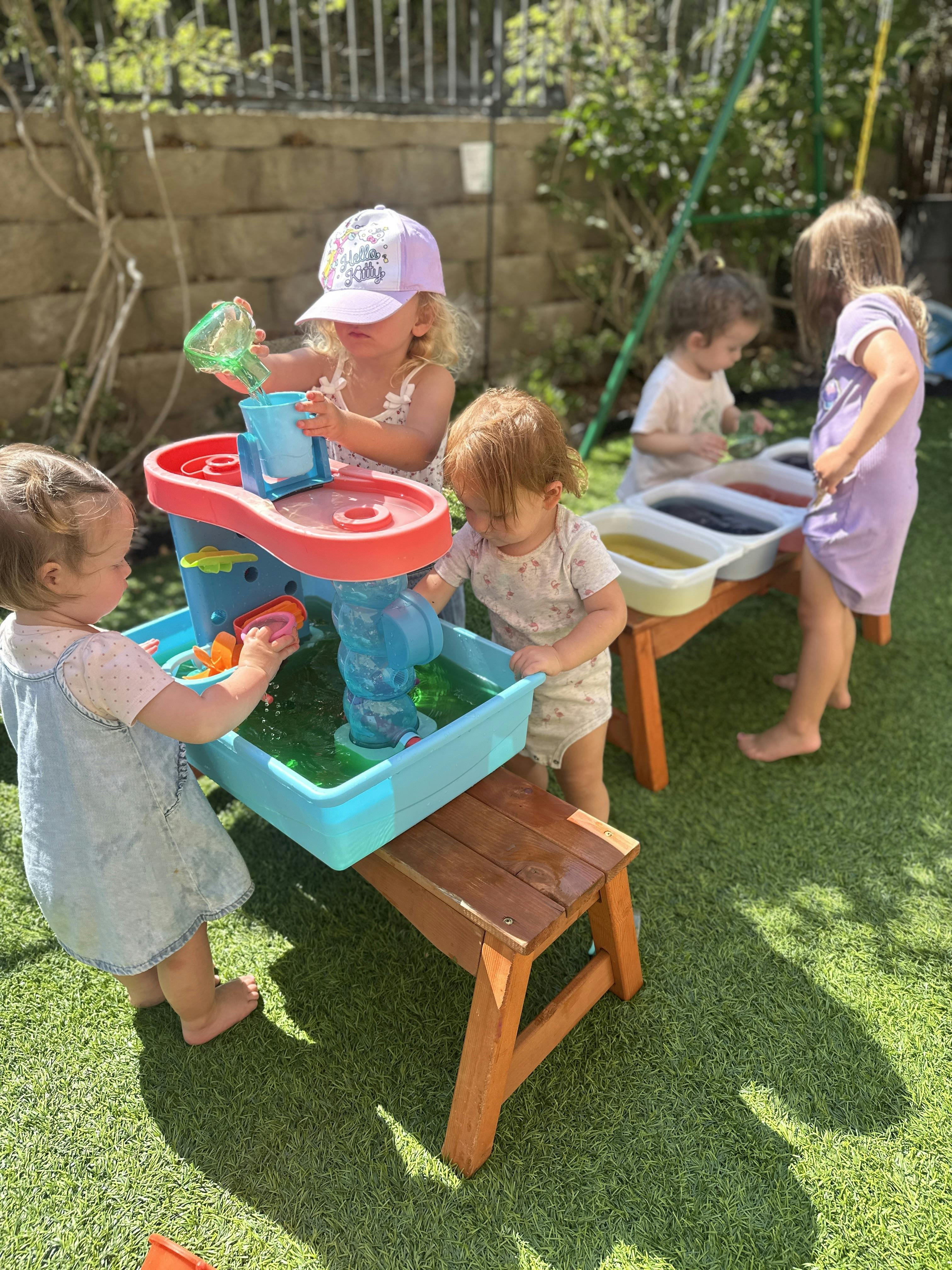 Children playing with water tables outdoors