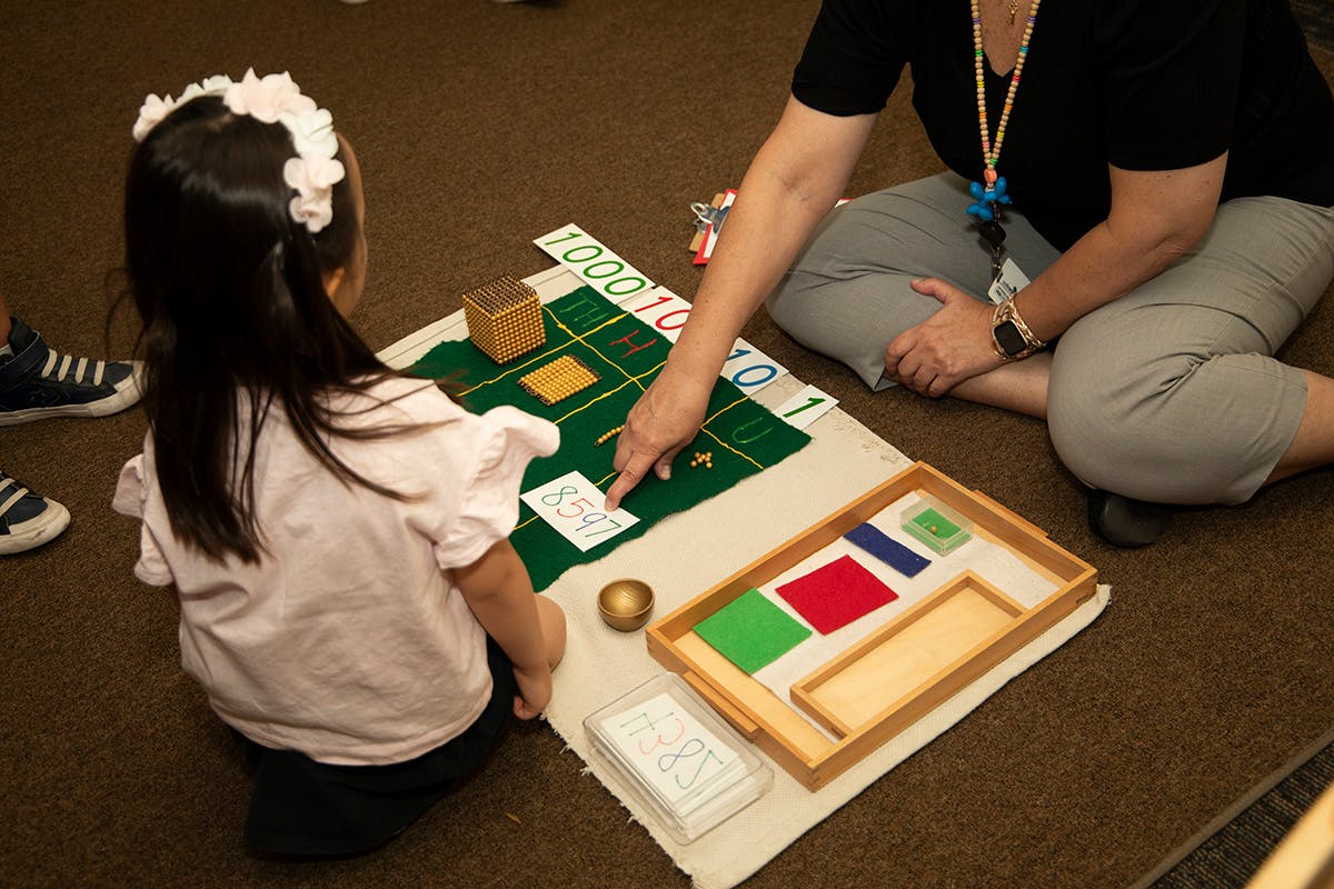 Adult and child on floor with learning materials