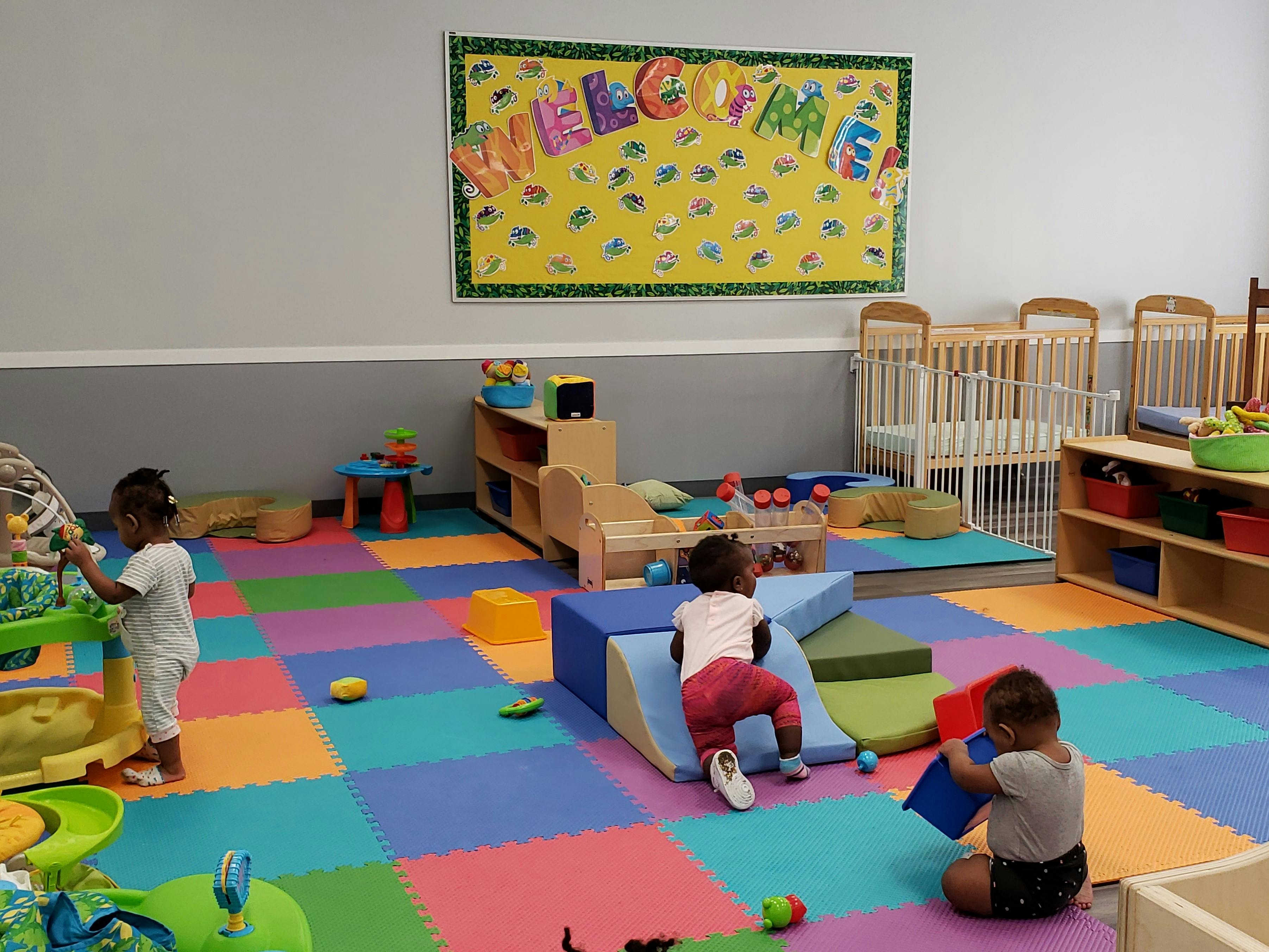 Children playing in a room with colorful floor mats and soft play equipment