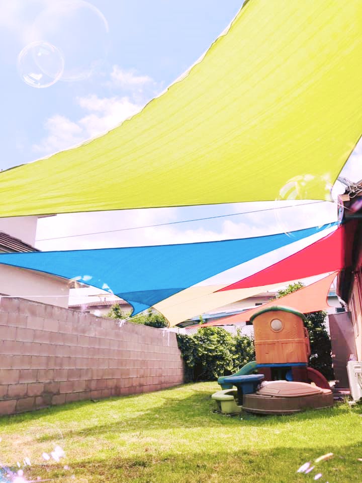 Colorful shade sails over a backyard with a play structure