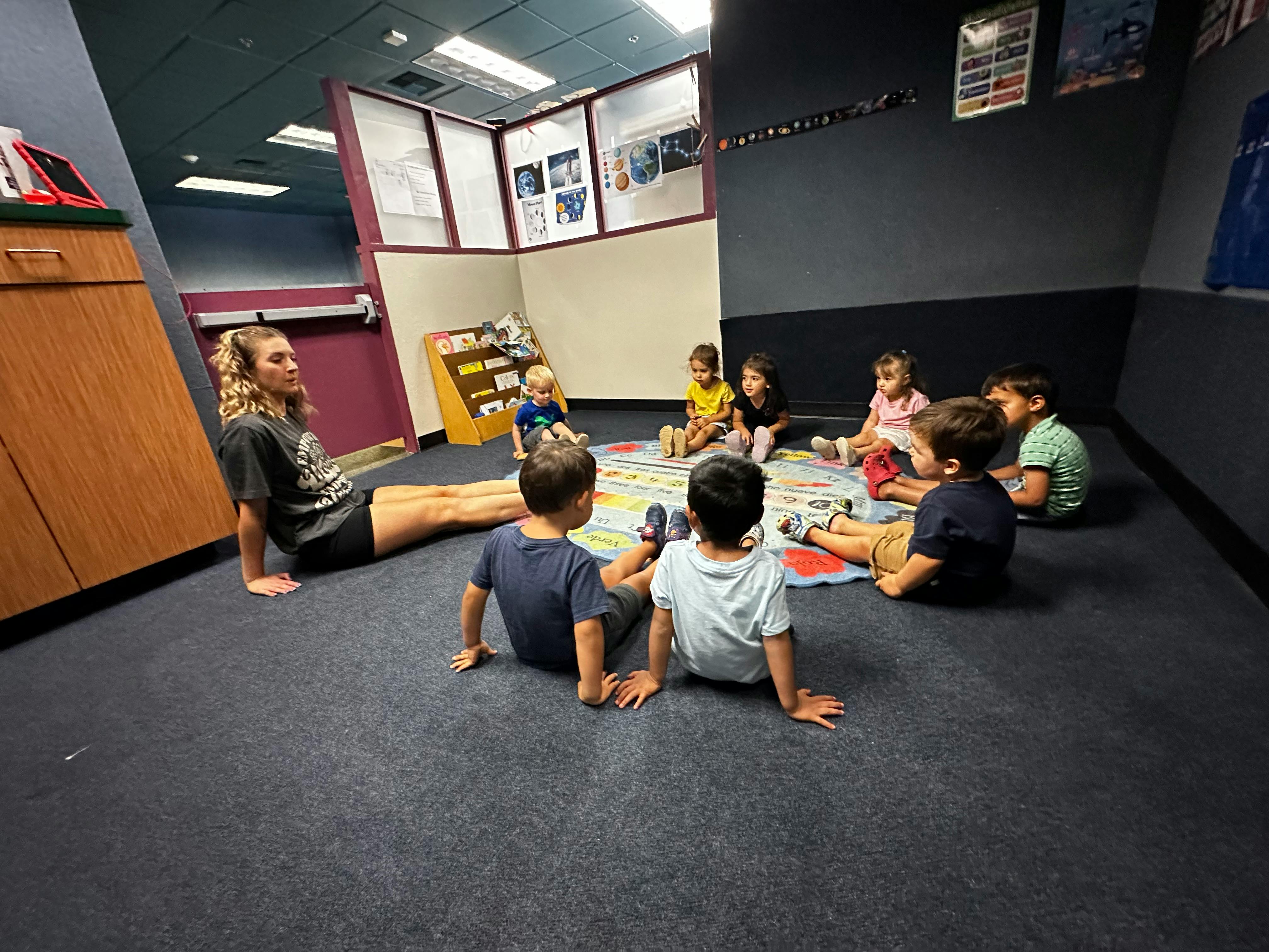 Person sitting on floor with children in a circle in a circle