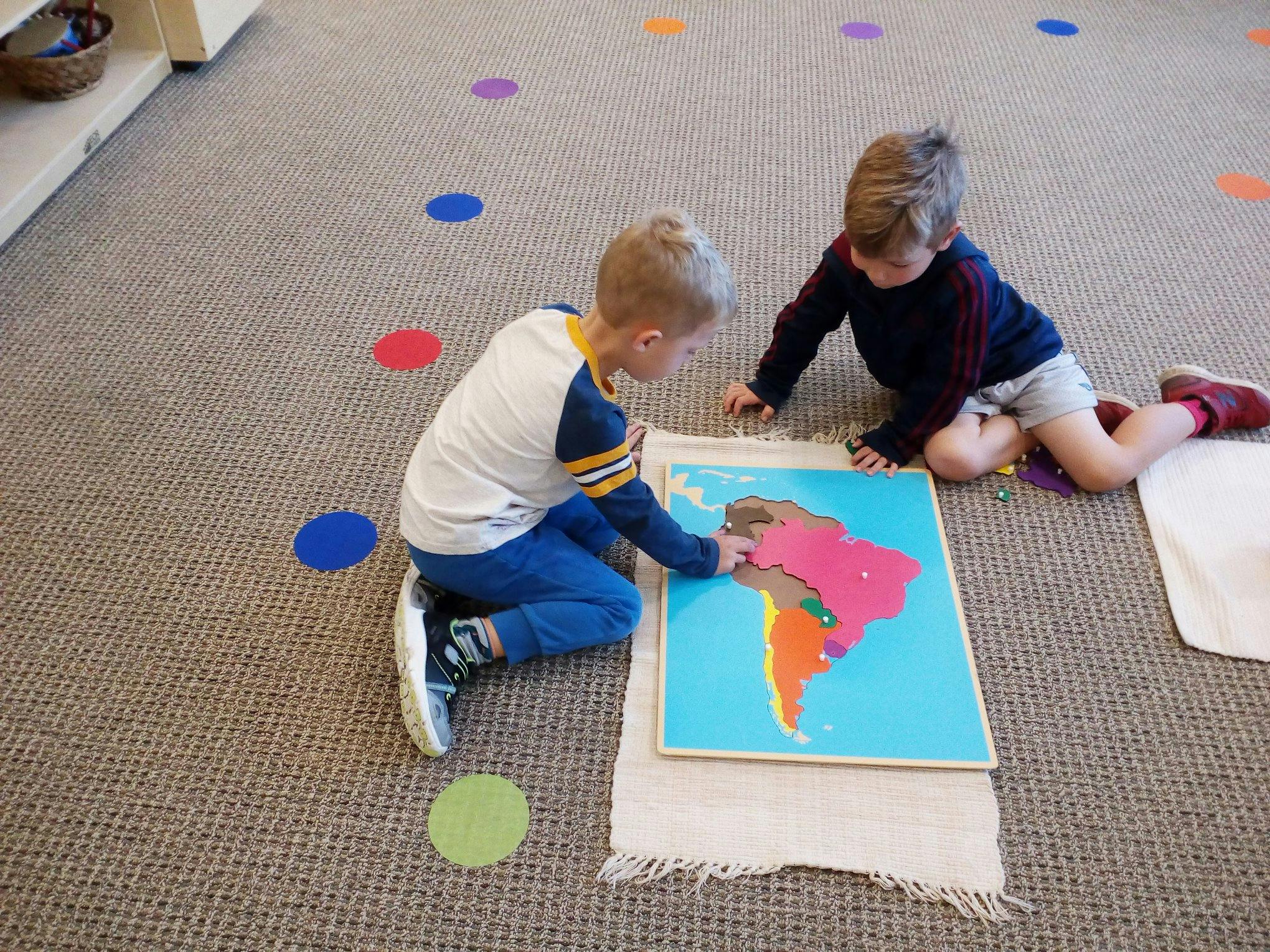 Two children on floor playing with a South America puzzle
