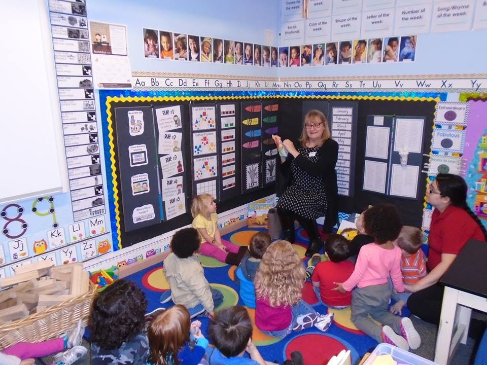 Adults and children sitting on a rug in a classroom
