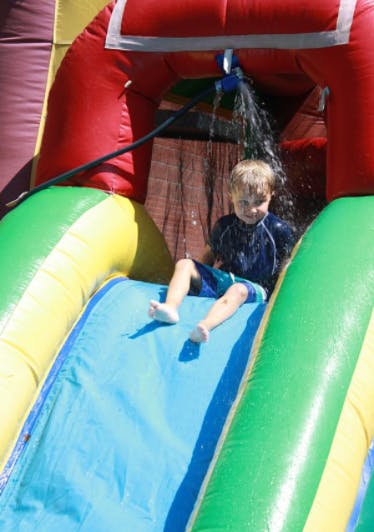 Child on an inflatable water slide with water spraying