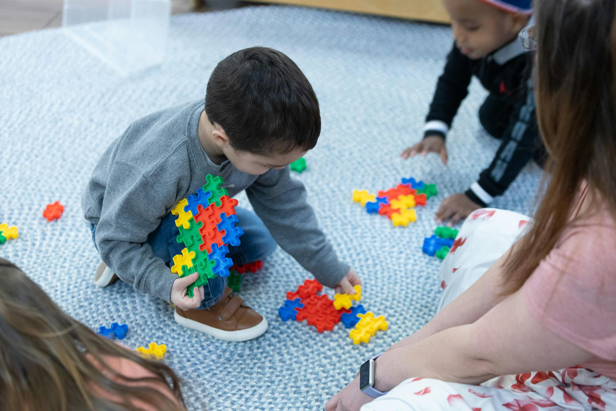Child playing with colorful interlocking plastic toys on a rug