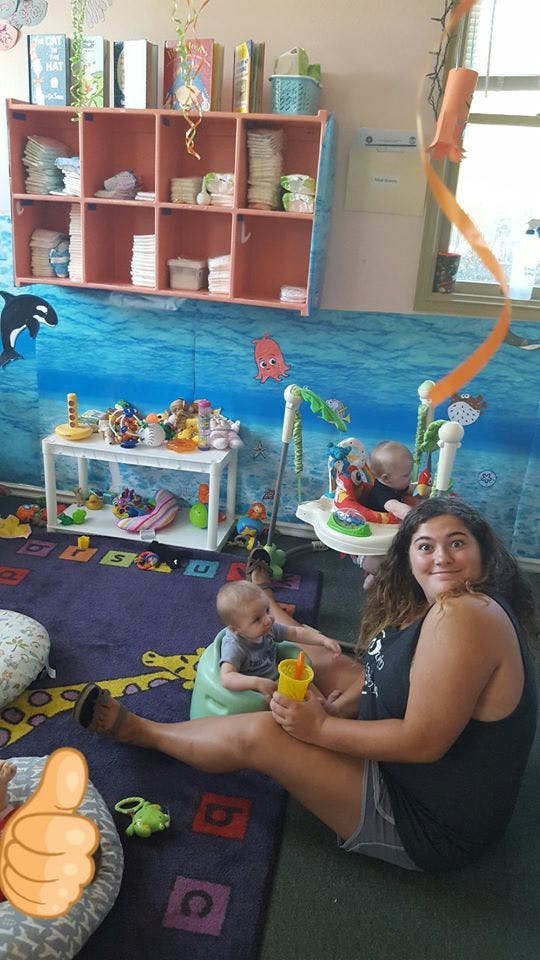 Person sitting on floor with two babies in a playroom