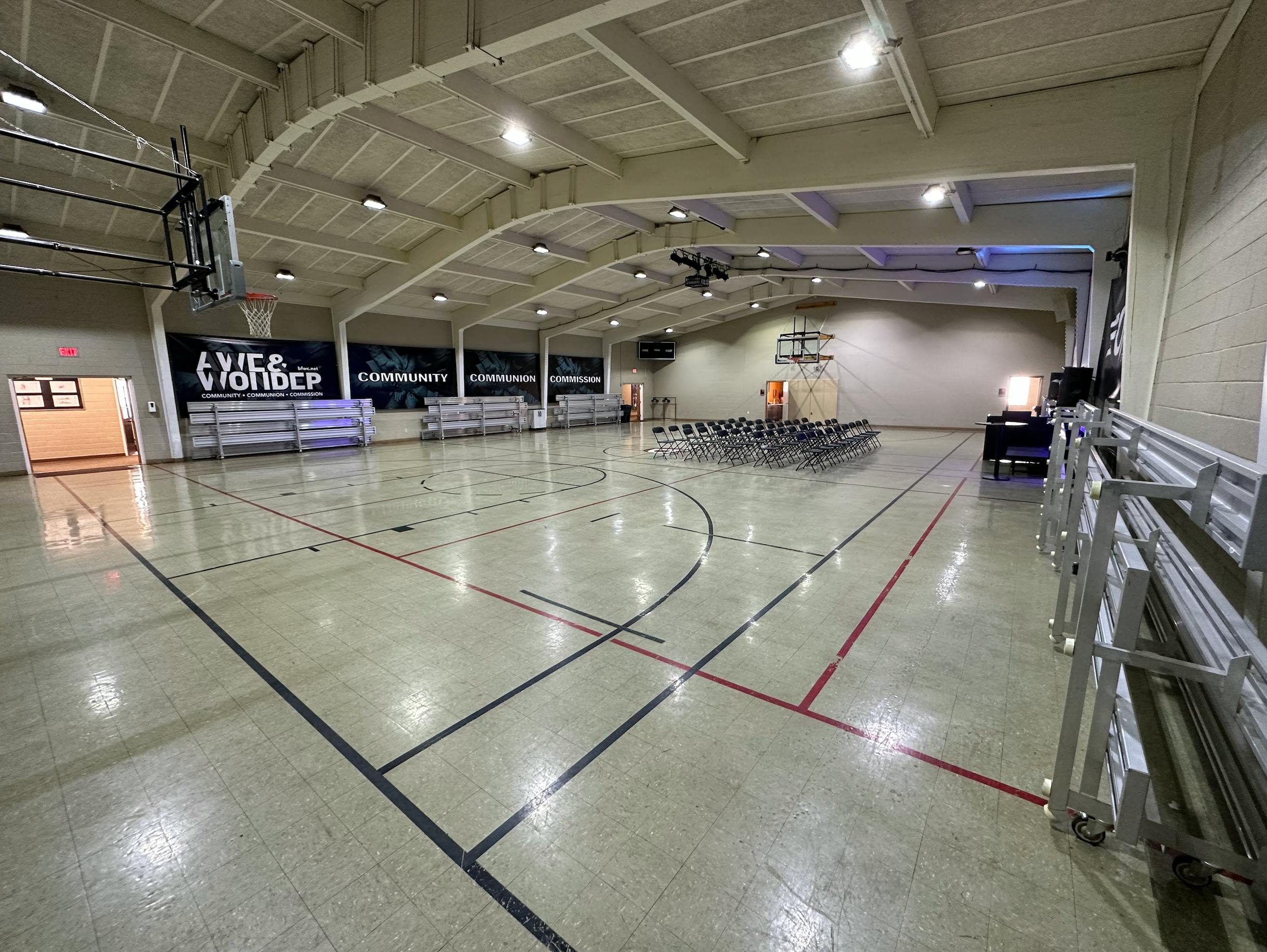 Empty indoor gymnasium with court lines and bleachers