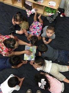 Adult and children on floor looking at a book