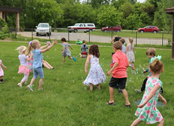 Children playing with bubbles in a grassy area