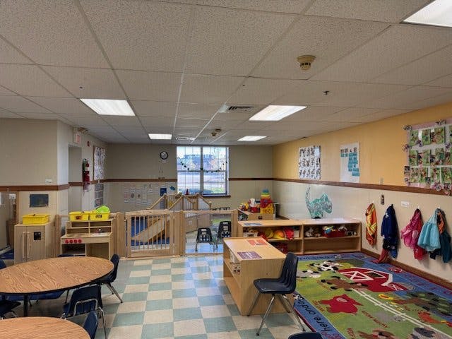 Empty classroom with small tables, chairs, and play areas