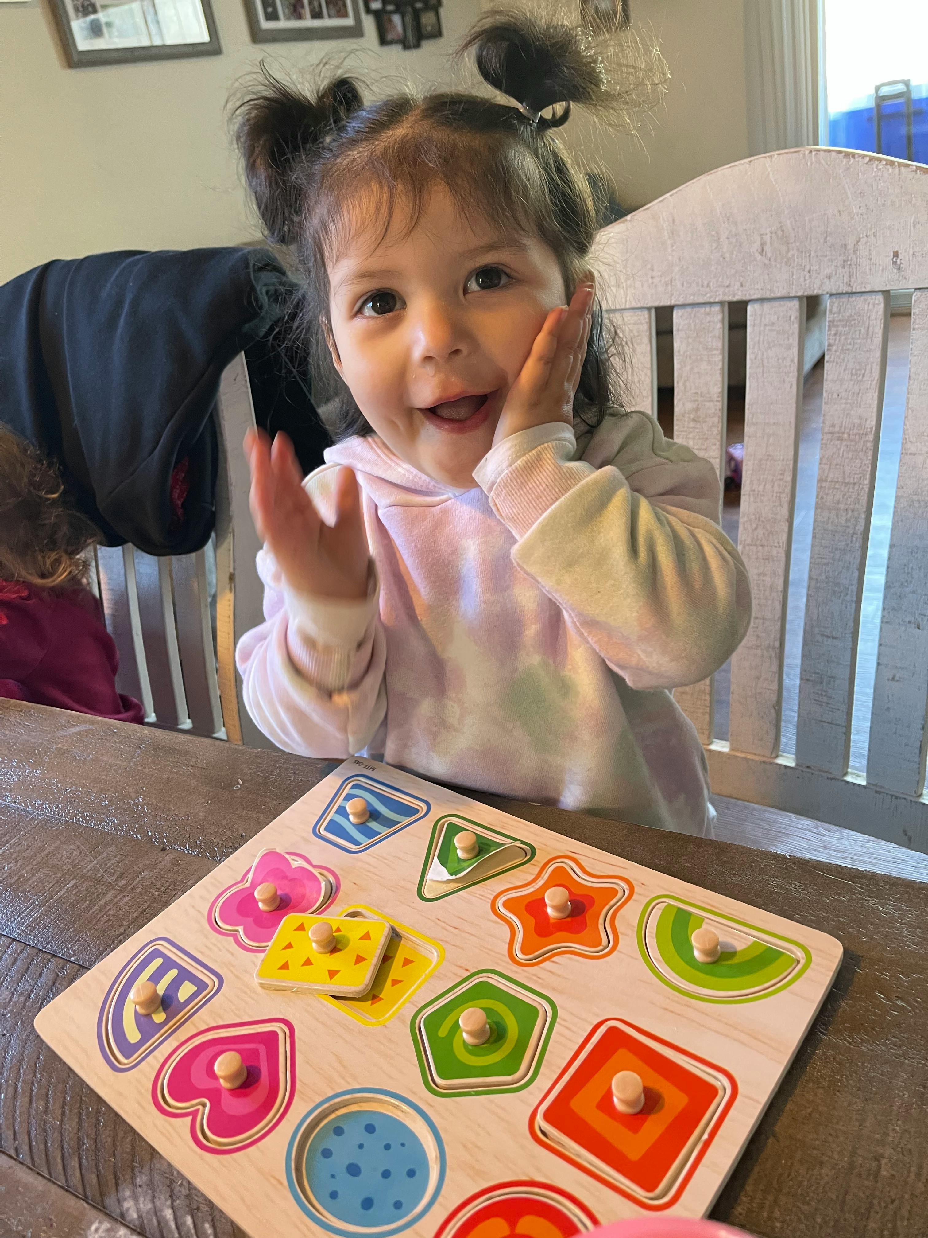 Child with pigtails playing with a shape sorter puzzle
