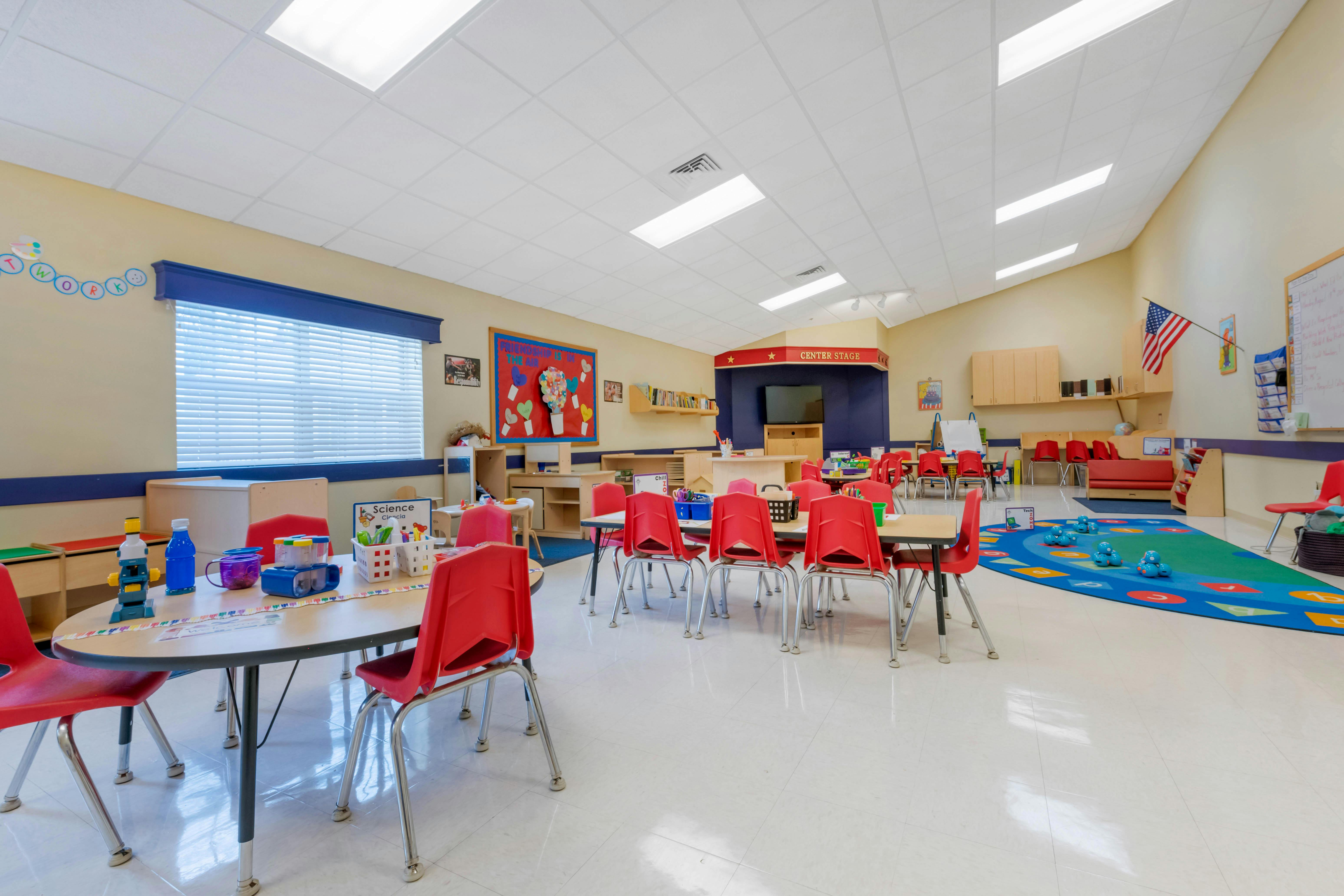Empty classroom with small tables and red chairs