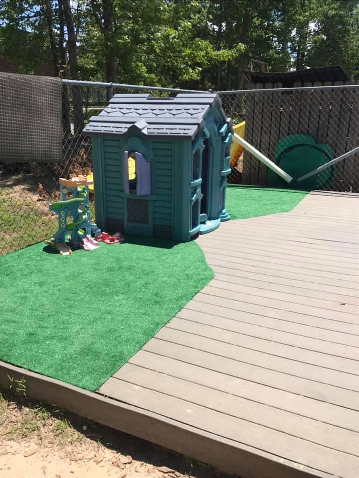 Playhouse on artificial turf next to a wooden deck