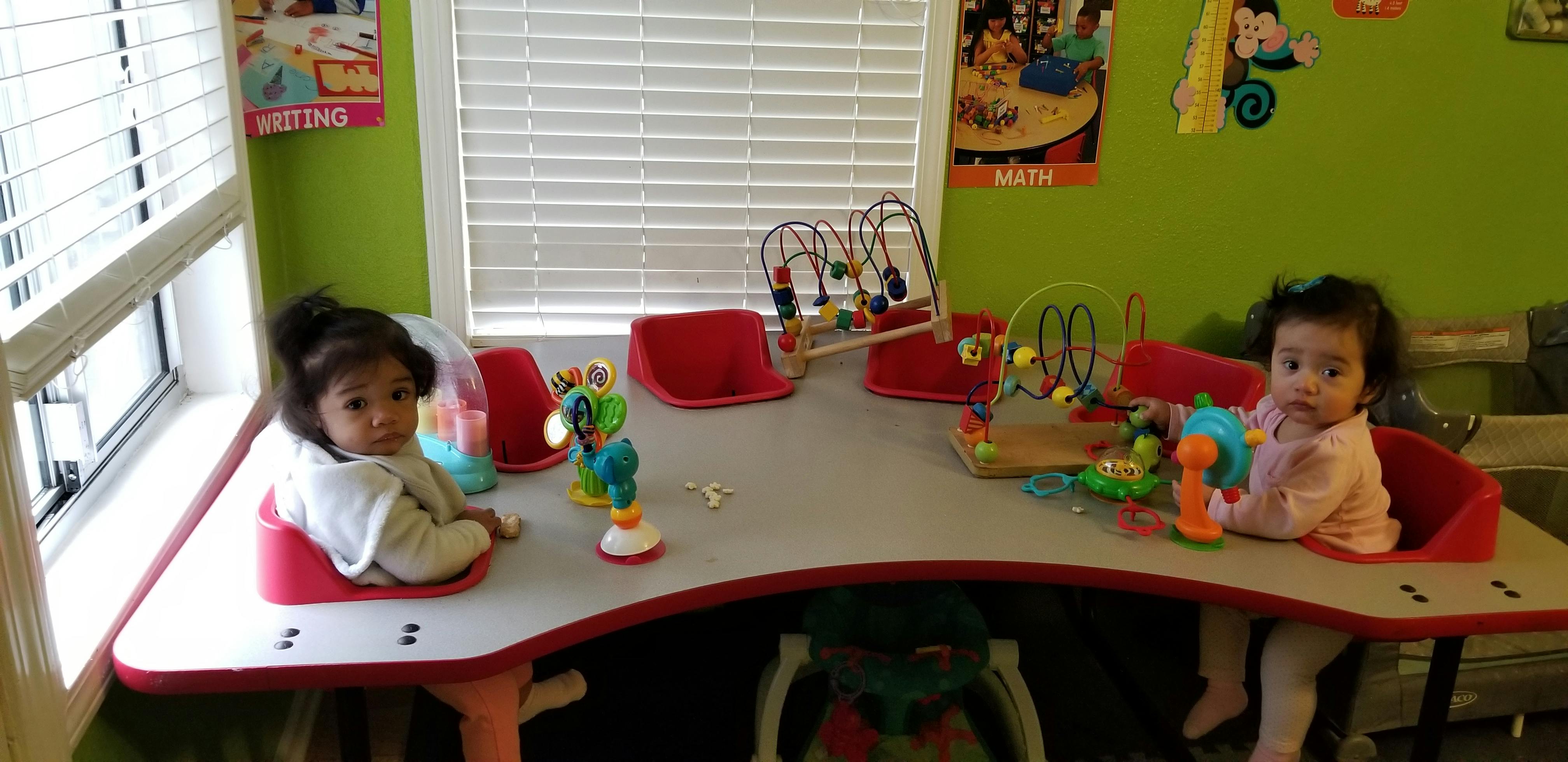 Two children sitting at a table with toys