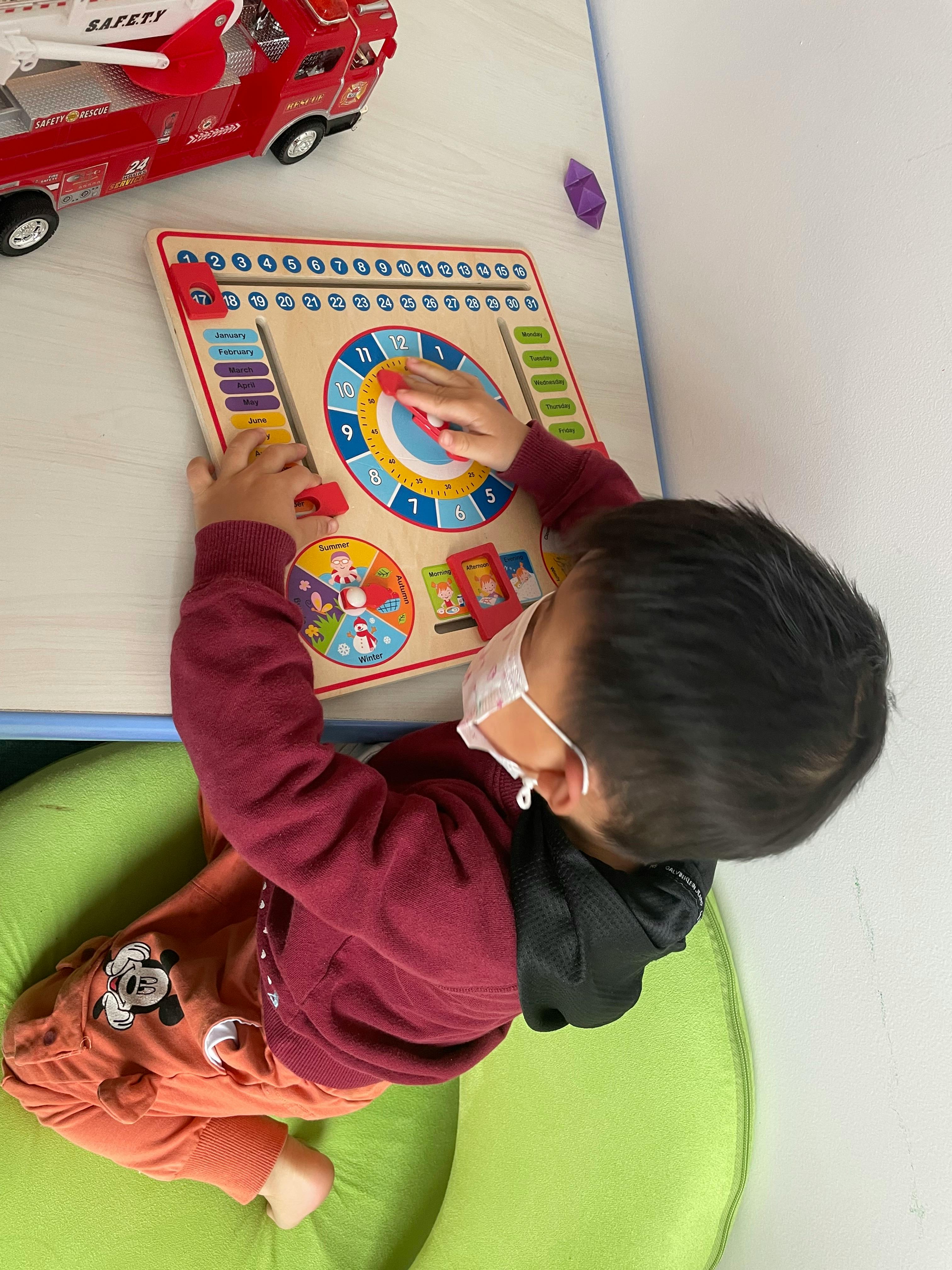 Child in a mask playing with a wooden activity board