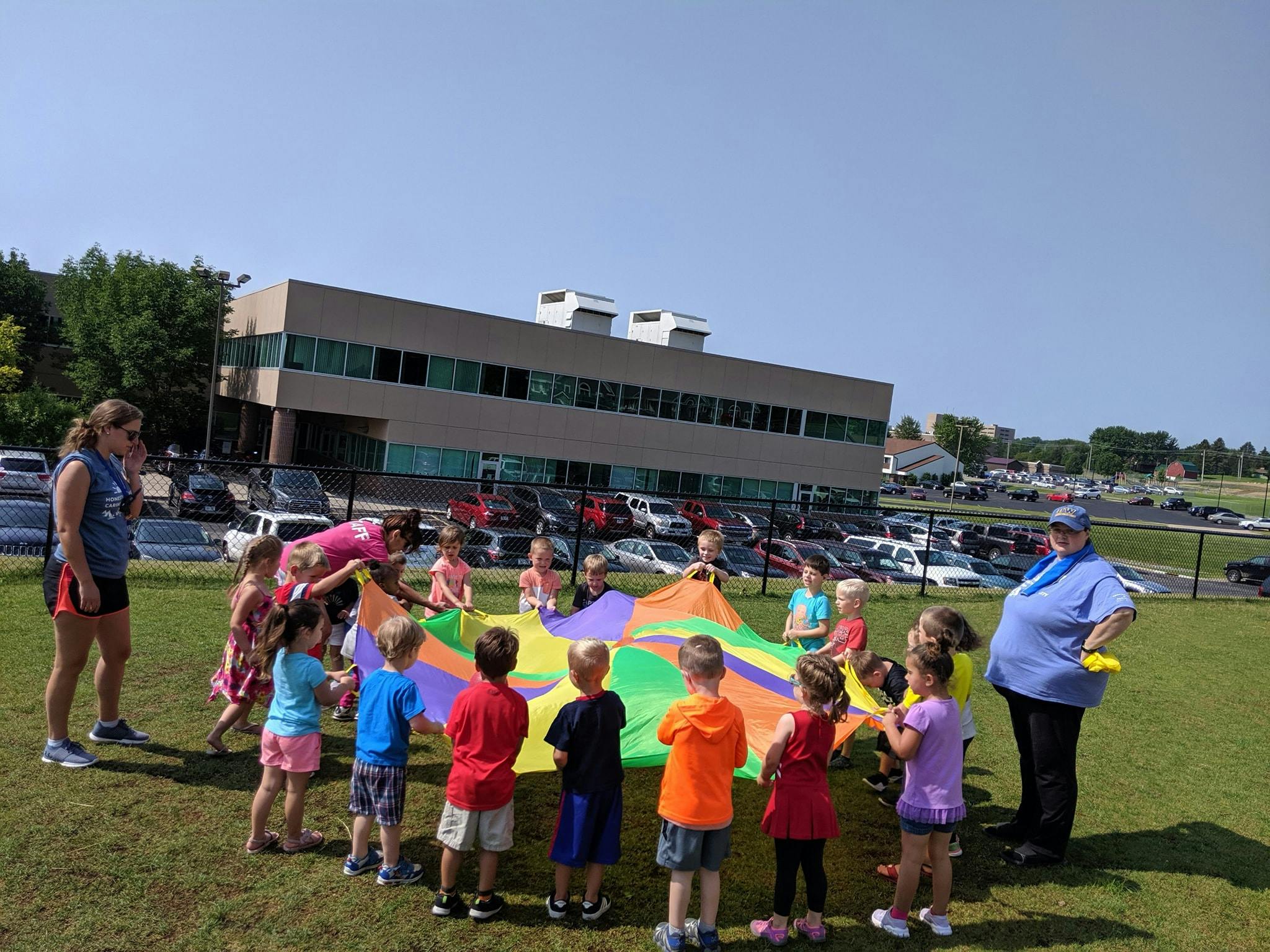 Adults and children playing with a colorful parachute outdoors